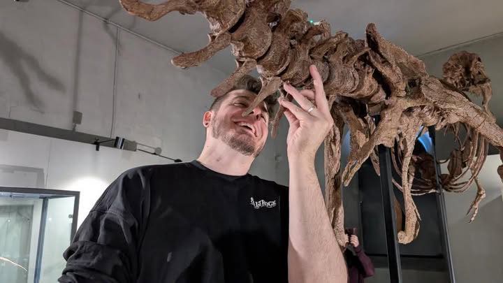 Alex Looking At Up At One Of The Studio'S Replica Dinosaur Skeletons.