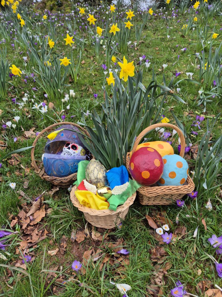 A Few Baskets Of Easter Eggs Arranged On The Grass Around Some Daffodils.